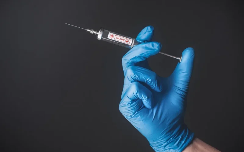 Frasco de vacina contra dengue em ambiente clínico com luvas e seringa