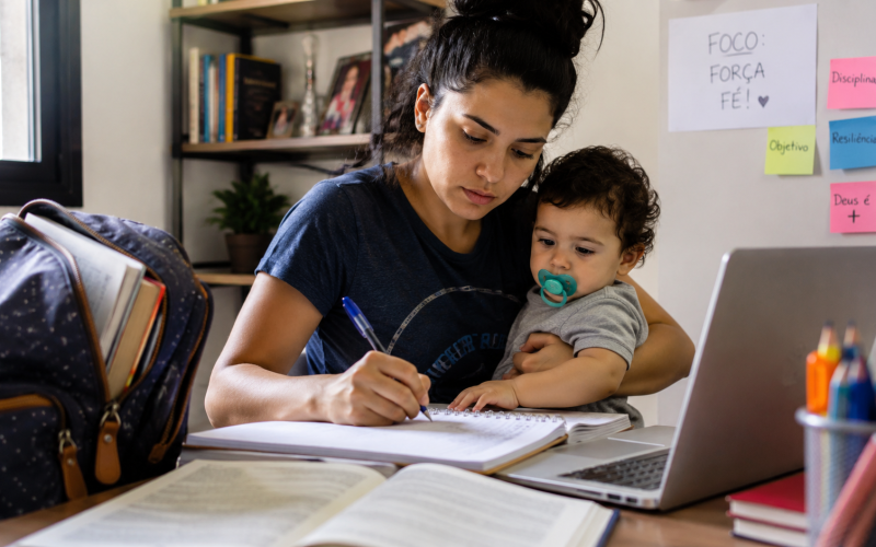 Mãe universitária estudando com o filho pequeno ao lado